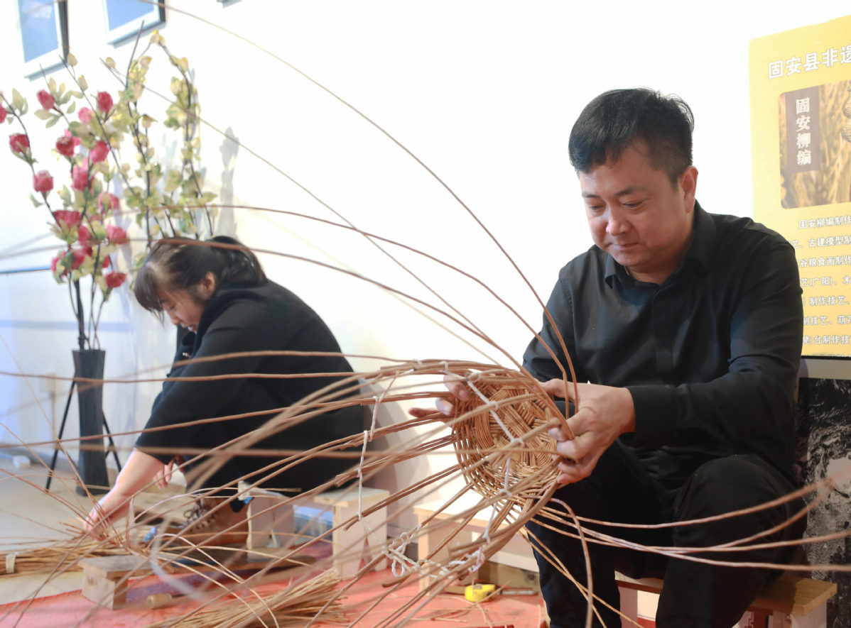 张万富（右）正在制作柳编工艺品。（固安县委组织部供图）.jpg